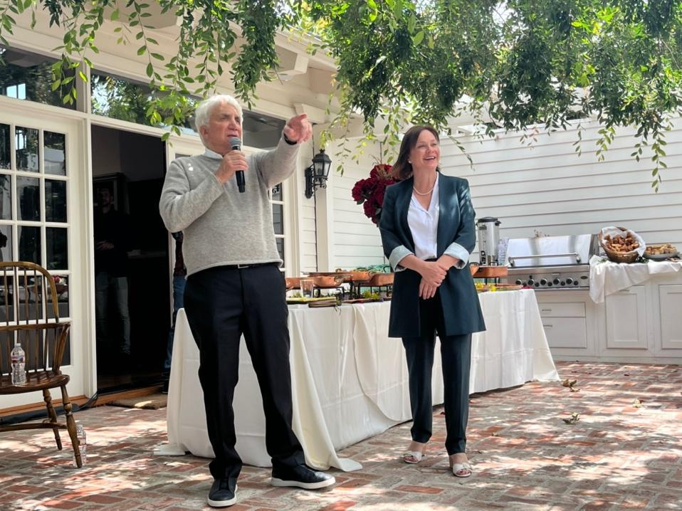 A person and person standing on a patio with a microphone
Description automatically generated with low confidence